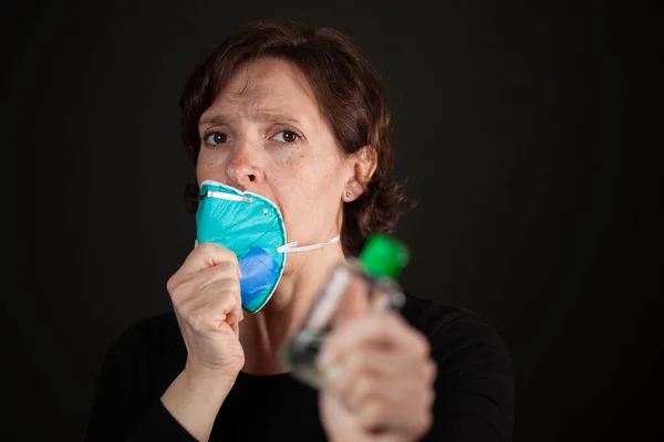 Woman pulls off face mask and picks up hand sanitizer