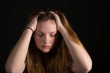 Siyah arka planda kafası elinde üzgün bir genç kız. Genç Depresyon Konsepti.