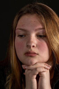 Siyah arka planda kafası elinde üzgün bir genç kız..