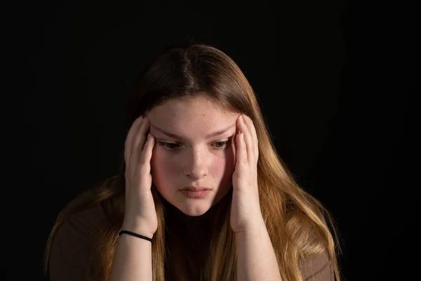 Smutné teen dívka na černém pozadí s hlavou v rukou. — Stock fotografie