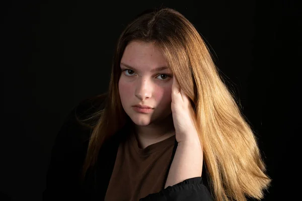 Triste ragazza adolescente su uno sfondo nero con la testa in mano . — Foto Stock