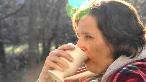 Kobieta na pokładzie wczesnym, chłodnym rankiem pije kawę z podnoszącą się parą. — Wideo stockowe