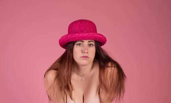 Pelirroja con llamativos ojos azules sobre un fondo rosa con un sombrero rosa —  Fotos de Stock