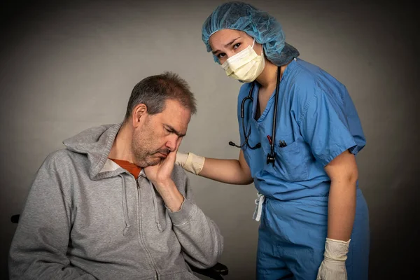 Oudere zieke man wordt verzorgd door een jonge verpleegster — Stockfoto