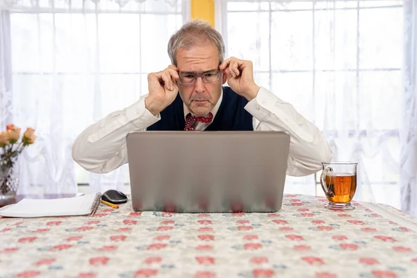 Az idősebb férfi beállítja a szemüvegét a hívás előtt. — Stock Fotó