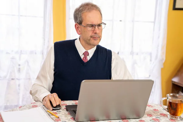 Középkorú férfi szemüveg dolgozik otthonról étkezőben fényes napon — Stock Fotó