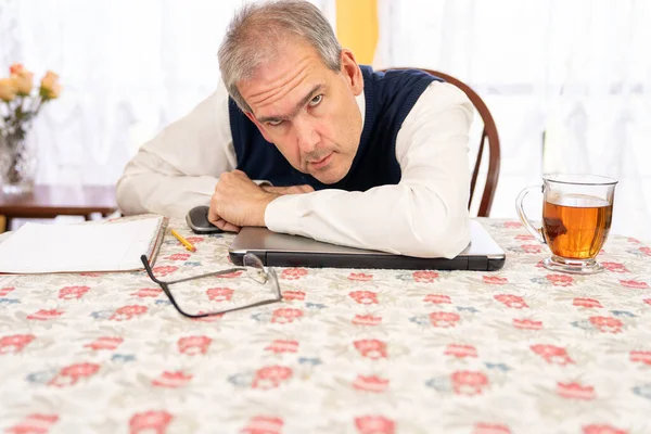Man van middelbare leeftijd werkt vanuit huis in de eetkamer op heldere dag — Stockfoto