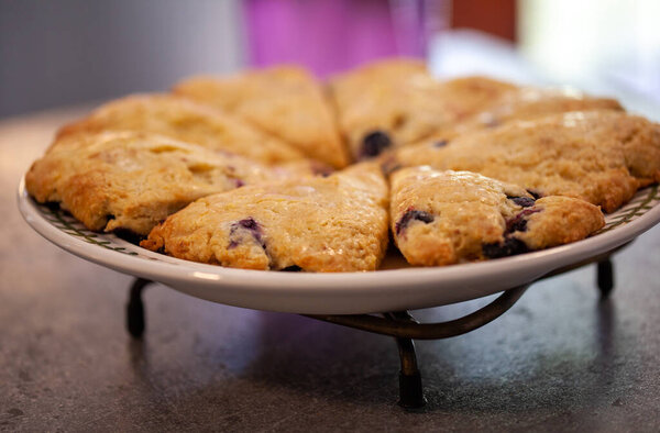 Черничные булочки, вырезанные треугольниками на круглой пластине крупным планом
.
