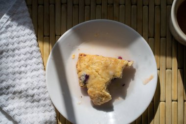 Doğal güneş ışığında yaban mersinli çörek ve bir fincan sıcak içecek yemek.. 