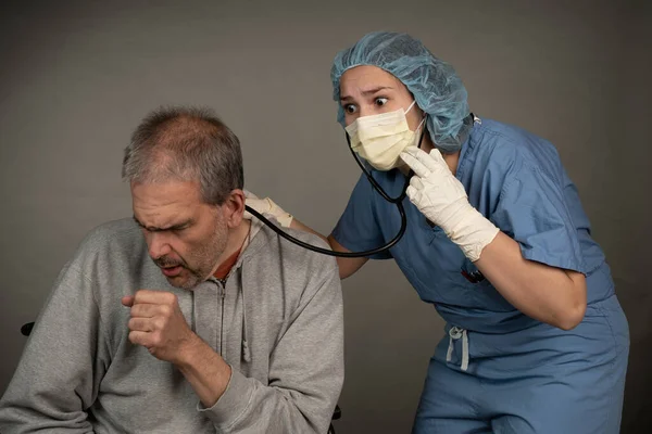 女性医护人员在忧心忡忡时，用听诊器倾听男性病人的胸部. — 图库照片