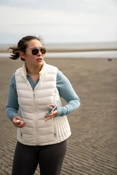 Kaukázusi nő a tengerparton telefonnal a kezében, nézi valami aggódó arc. — Stock Fotó