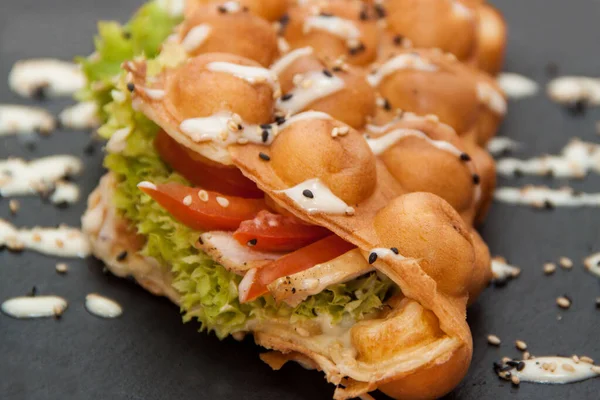 Hong Kong waffle 'ı. Salatalı waffle, domates ve tepside tavuk. Domatesli waffle salatası, mayonez ve susam tohumları serpiştirilmiş..
