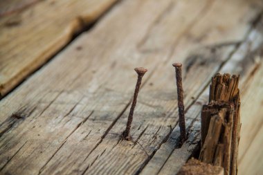 Ahşap arka planda iki paslı çivinin soyutlanması.