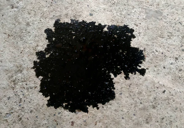 Beton zeminde yağ lekesi var. Gri desenli betonda siyah nokta.