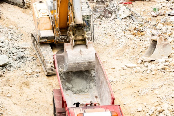 Grävmaskin sätter stenar och skräp i lastbil — Stockfoto