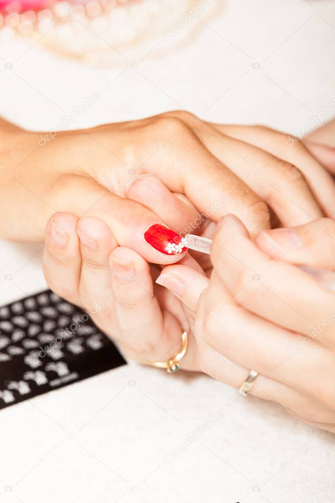 manicurist decorating nail of client