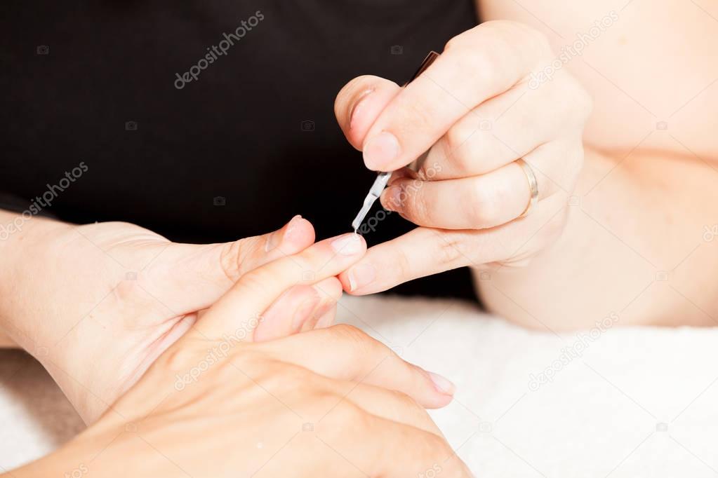 esthetician decorating nails of female client in salon 
