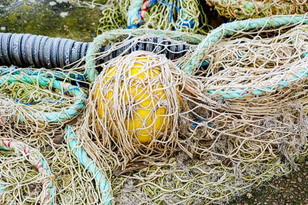 Blue fishing net on a pontoon with its ropes and floats covered — Stock Photo, Image