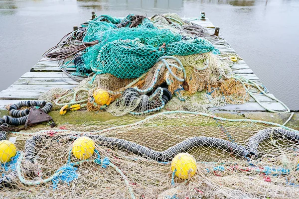 Blue fishing net on a pontoon with its ropes and floats covered — Stock Photo, Image