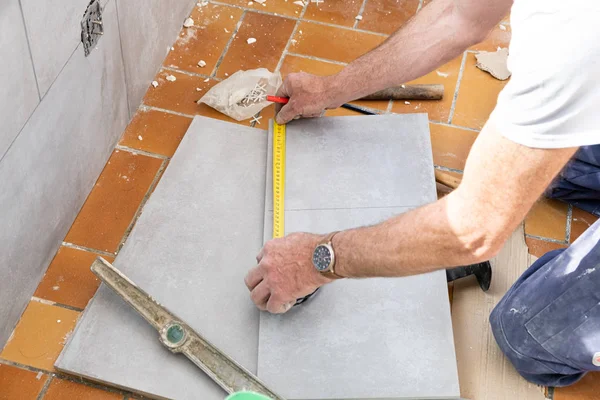 The tiler measures the tile before cutting it — Stock Photo, Image