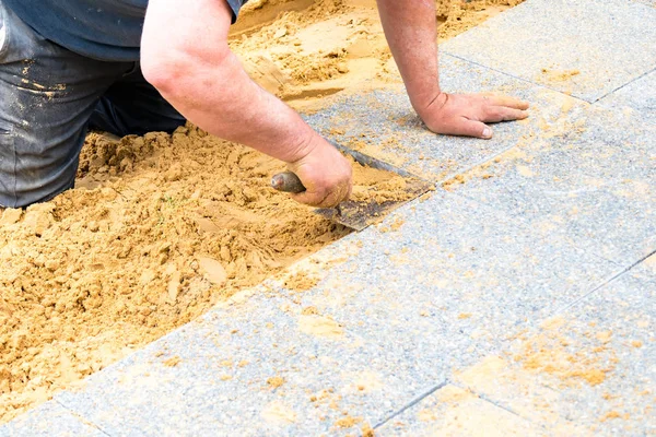 Der Maurer legt Kiesplatten auf Sand, um eine Gasse zu bilden — Stockfoto