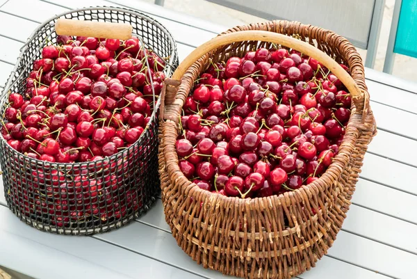 Two baskets filled with beautiful red cherries on a garden table — Stock Photo, Image