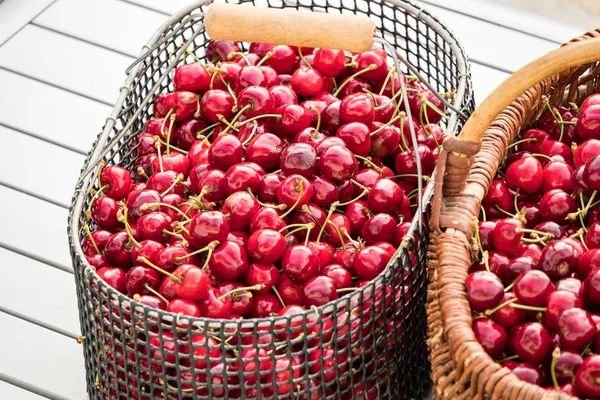 Две корзины, наполненные красивыми красными вишнями на садовом столе — стоковое фото