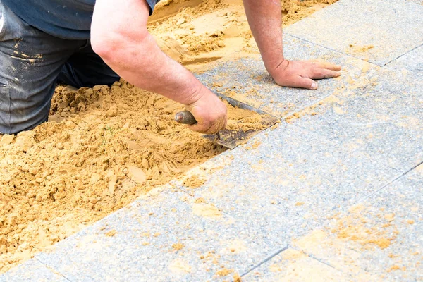 The mason lays gravel slabs on sand to make an alley — Stock Image The mason lays gravel slabs on sand to make an alley Stock Photo