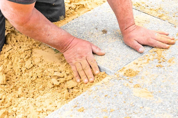 Der Maurer legt Kiesplatten auf Sand, um eine Gasse zu bilden — Stockfoto