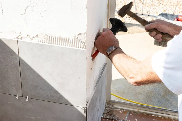 Der Maurer bereitet die Wand mit einem Meißel vor, bevor er eine Keramik verlegt — Stockfoto