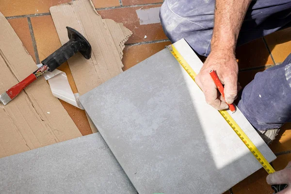 El tiler mide la baldosa antes de cortarla —  Fotos de Stock