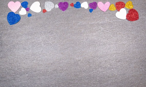 Cuori colorati di brillantini di tutti i colori su un dorso in granito grigio — Foto Stock