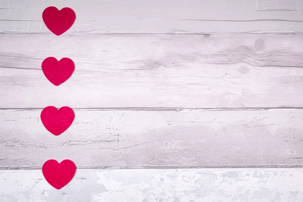 Red felt hearts on a background of old wooden planks resembling — Stock Photo, Image