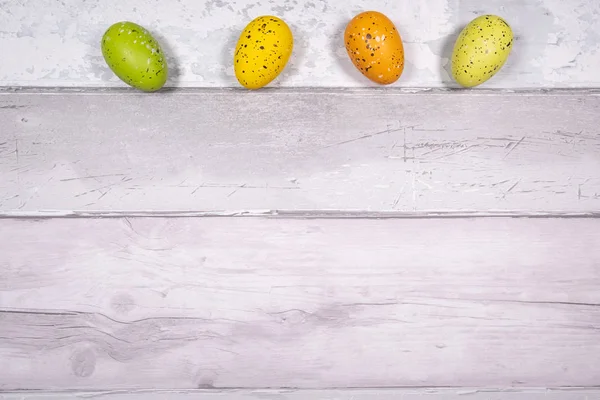 Uova di Pasqua gialle verdi e arancioni su uno sfondo di legno antico — Foto Stock
