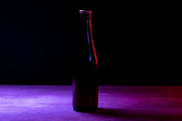 带有红光和紫光的黑色背景啤酒瓶的轮廓 — 图库照片
