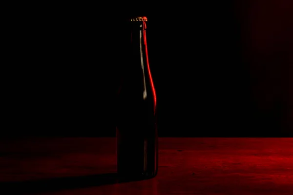 在黑色背景上的啤酒瓶的轮廓 红色的灯光从一边照亮了它 — 图库照片