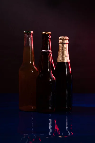 Cuatro Botellas Cerveza Sobre Fondo Negro Púrpura Con Reflejos Sobre —  Fotos de Stock