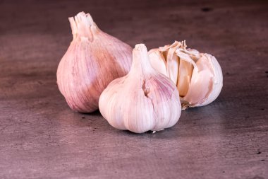 Mutfak tezgahında üç büyük baş pembe sarımsak.