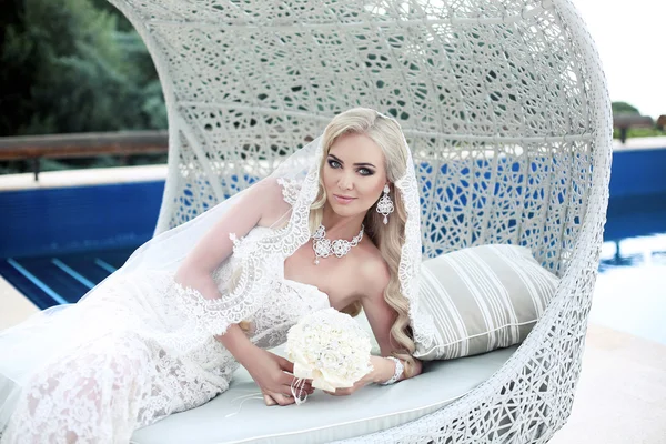 Wedding portrait beautiful blonde bride lying on beach sofa in f — Stock Photo, Image