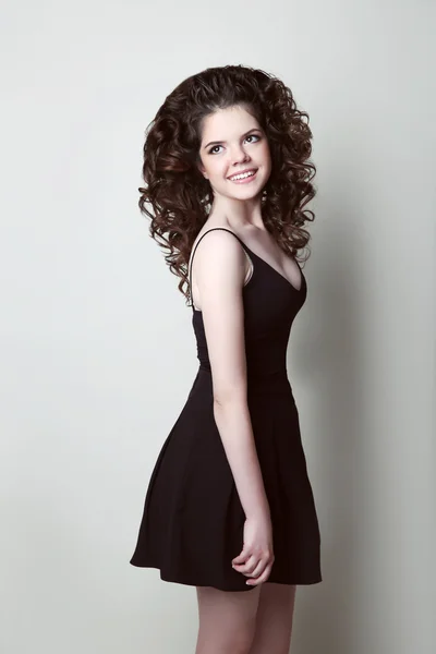 Happy teen girl with curly hair isolated on studio grey backgrou — Stock Photo, Image