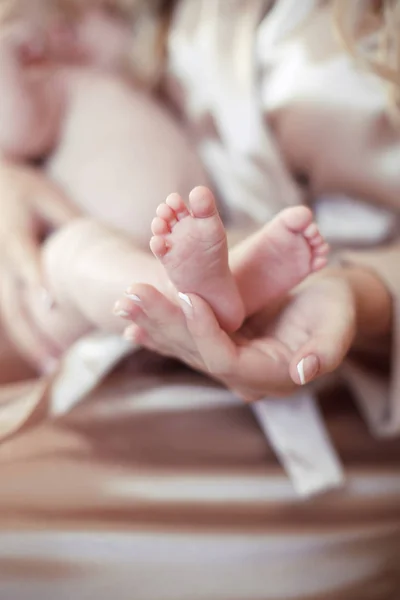 Nyfödd Baby fötter i mor händer närbild — Stockfoto