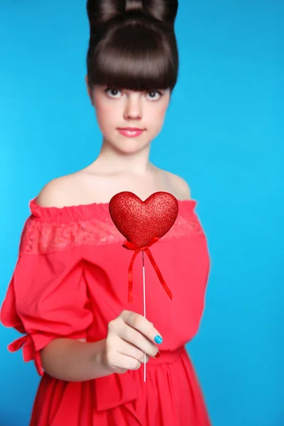 Červené srdce v ruce dívenky. Bruneta mladá model s lukem vlasy — Stock fotografie