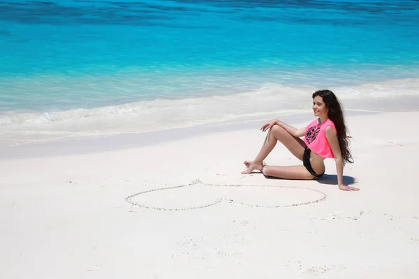 Menina modelo biquíni despreocupado com o coração na areia relaxante em exótico — Fotografia de Stock