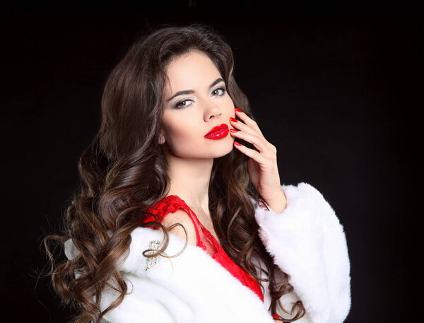 Beautiful Fashion brunette Girl portrait in white Mink Fur Coat. Red lips makeup. Beauty Luxury winter woman with long curly hair style posing isolated on studio black background.