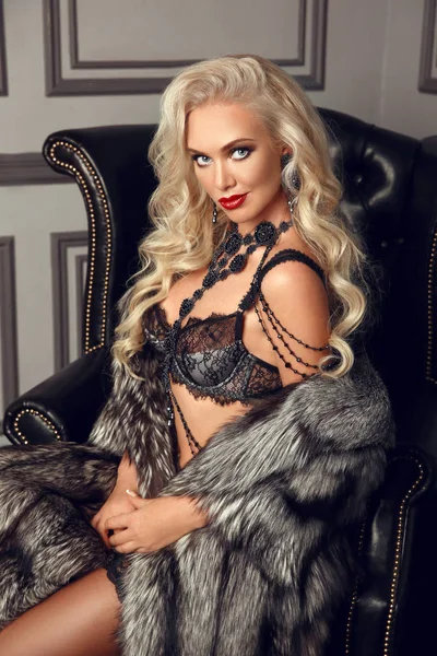 Belle femme blonde glamour en lingerie sexy assise en noir — Photo
