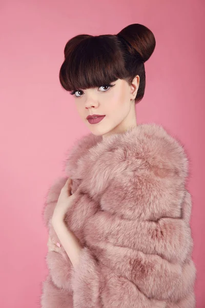 Penteado de pão de beleza. Moda adolescente modelo de menina em casaco de pele rosa . — Fotografia de Stock