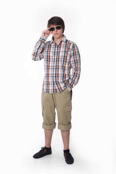 Jonge mode man poseren in ingecheckte shirt en zwarte zonnebril. — Stockfoto