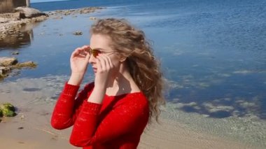 Kadın çalışan el sahilde deniz rüzgarda üfleme kıvırcık saçlarının arasından portresi kapatın. Mavi gökyüzü üzerinde mutlu erkek.