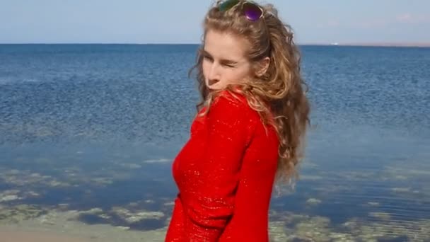 Close up retrato de mulher correndo mão através do cabelo encaracolado soprando no vento pelo mar na praia. Mulher feliz sobre o céu azul . — Vídeo de Stock