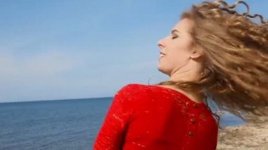 Kadın çalışan el sahilde deniz rüzgarda üfleme kıvırcık saçlarının arasından portresi kapatın. Mavi gökyüzü üzerinde mutlu erkek